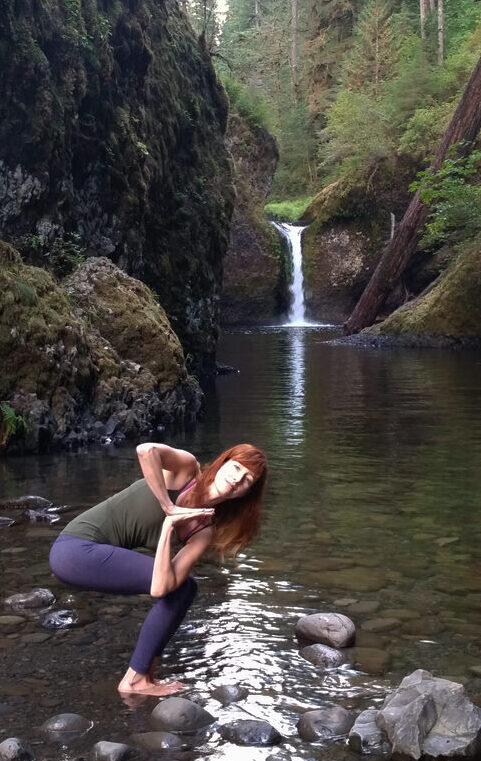 Megan in chair pose in a natural setting with waterfall.